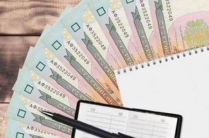 100 Ukrainian hryvnias bills fan and notepad with contact book and black pen. Concept of financial planning and business strategy photo