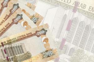 Los billetes de 200 dirhams de los emiratos árabes unidos se encuentran apilados en el fondo de un gran billete semitransparente. fondo de negocios abstracto foto