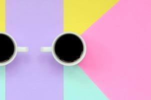 Small white coffee cup on texture background of fashion pastel blue, yellow, violet and pink colors paper in minimal concept photo