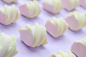 Colorful marshmallow laid out on violet paper background. pastel creative textured pattern. Perspective macro shot photo