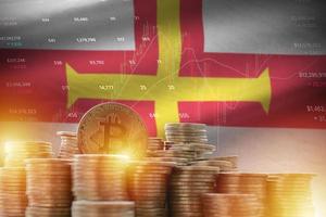 Guernsey flag and big amount of golden bitcoin coins and trading platform chart. Crypto currency photo