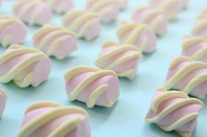 Colorful marshmallow laid out on blue paper background. pastel creative textured pattern. Perspective macro shot photo