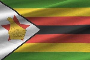 bandera de zimbabwe con grandes pliegues ondeando de cerca bajo la luz del estudio en el interior. los símbolos y colores oficiales en banner foto