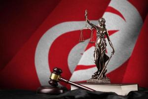 Tunisia flag with statue of lady justice, constitution and judge hammer on black drapery. Concept of judgement and guilt photo