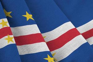 Cabo verde flag with big folds waving close up under the studio light indoors. The official symbols and colors in banner photo