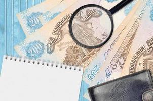 200 Ukrainian hryvnias bills and magnifying glass with black purse and notepad. Concept of counterfeit money. Search for differences in details on money bills to detect fake photo