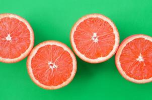 Top view of a several grapefruit slices on bright background in green color. A saturated citrus texture image photo