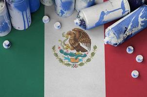 Mexico flag and few used aerosol spray cans for graffiti painting. Street art culture concept photo