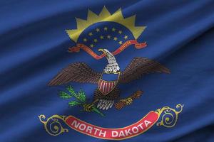 North Dakota US state flag with big folds waving close up under the studio light indoors. The official symbols and colors in banner photo