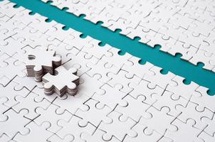 The blue path is laid on the platform of a white folded jigsaw puzzle. The missing elements of the puzzle are stacked nearby. Texture image with space for text photo