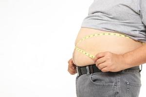 Fat Asian men use a yellow tape measure. Measure your belly size. Concept of weight loss, health problems of obese people. White background. isolated. Copy space photo