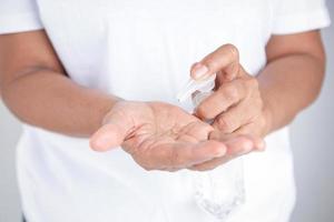 una anciana vestida de blanco se lava las manos con gel de alcohol. prevenir la infección por el coronavirus. concepto de protección contra el virus covid-19 foto