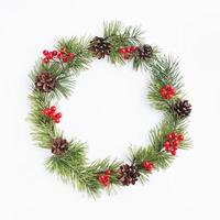 Pine christmas wreath decorated with cones and red berry fruits on white background photo