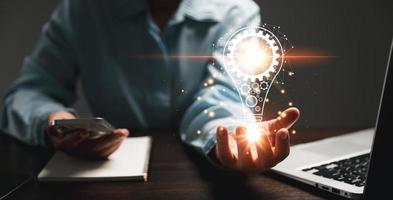 Hand of woman with light bulb and there is gear icon and using laptop computer. Innovation idea concept. Concept of brainstorming inspiration creatively. photo
