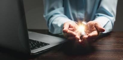 Hand of woman with light bulb and there is gear icon and using laptop computer. Innovation idea concept. Concept of brainstorming inspiration creatively. photo