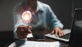 Hand of woman with light bulb and there is gear icon and using laptop computer. Innovation idea concept. Concept of brainstorming inspiration creatively. photo