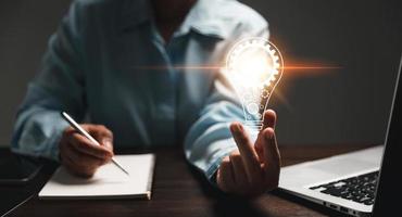 Hand of woman with light bulb and there is gear icon and using laptop computer. Innovation idea concept. Concept of brainstorming inspiration creatively. photo