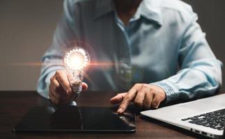 Hand of woman with light bulb and there is gear icon and using laptop computer. Innovation idea concept. Concept of brainstorming inspiration creatively. photo