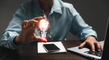 Hand of woman with light bulb and there is gear icon and using laptop computer. Innovation idea concept. Concept of brainstorming inspiration creatively. photo