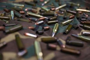 Many rifle bullets and cartridges on dark camouflage background