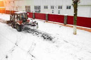 red snow plow tractor clears sidewalks rear view. photo