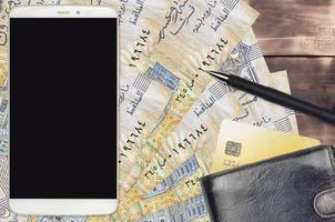 Billetes de 25 piastras egipcias y smartphone con monedero y tarjeta de crédito. pagos electrónicos o concepto de comercio electrónico. compras y negocios en línea con dispositivos portátiles foto