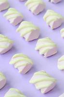 Colorful marshmallow laid out on violet paper background. pastel creative textured pattern. Perspective macro shot photo