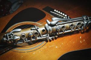 An antique clarinet resting on acoustic guitar photo