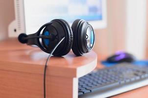 Big black headphones lie on the wooden desktop of the sound designer photo