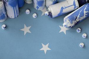 Micronesia flag and few used aerosol spray cans for graffiti painting. Street art culture concept photo