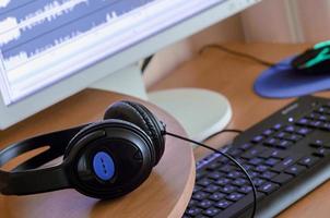 Big black headphones lie on the wooden desktop of the sound designer photo