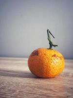 This is a photo of a small orange on a wooden table.