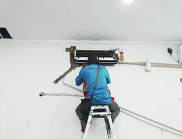 West Java, Indonesia in July 2022. A technician is repairing and cleaning a broken home Air Conditioner. photo