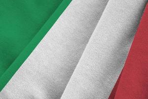 Italy flag with big folds waving close up under the studio light indoors. The official symbols and colors in banner photo