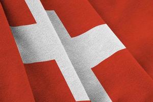 Switzerland flag with big folds waving close up under the studio light indoors. The official symbols and colors in banner photo