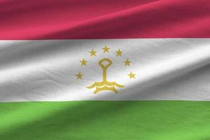 Tajikistan flag with big folds waving close up under the studio light indoors. The official symbols and colors in banner photo