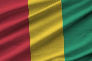 Guinea flag with big folds waving close up under the studio light indoors. The official symbols and colors in banner photo