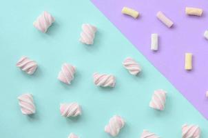 Colorful marshmallow laid out on violet and blue paper background. pastel creative textured pattern. minimal photo