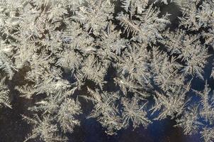 Snowflakes frost rime macro on window glass pane photo