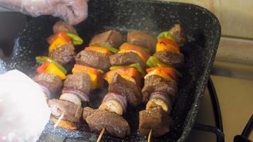 espetadas de carne marinada com legumes preparados na grelha. o cozinheiro vira a carne para fritar em outro lugar video