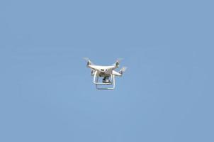 Big white drone hovering in a bright cloudless blue sky photo