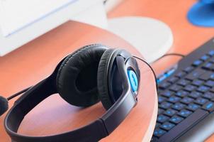 Big black headphones lie on the wooden desktop of the sound designer photo