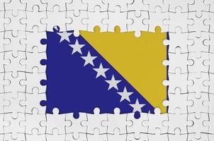 Bosnia and Herzegovina flag in frame of white puzzle pieces with missing central part photo