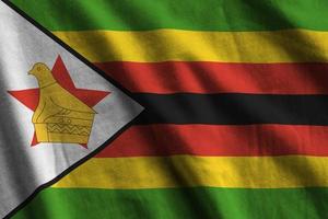 bandera de zimbabwe con grandes pliegues ondeando de cerca bajo la luz del estudio en el interior. los símbolos y colores oficiales en banner foto