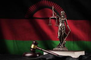 bandera de malawi con estatua de la dama de la justicia, constitución y martillo de juez sobre cortinas negras. concepto de juicio y culpa foto