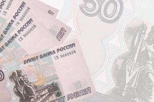 50 russian rubles bills lies in stack on background of big semi-transparent banknote. Abstract business background photo