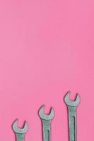 tres llaves metálicas yacen sobre la textura del fondo del papel de color rosa pastel de moda en un concepto mínimo