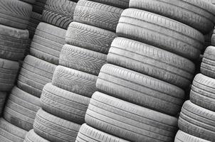 Old used tires stacked with high piles in secondary car parts shop garage photo