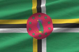 Dominica flag with big folds waving close up under the studio light indoors. The official symbols and colors in banner photo