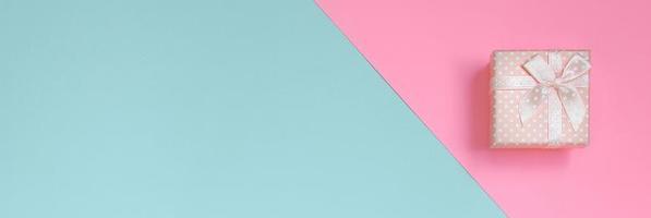 Small pink gift box lie on texture background of fashion pastel blue and pink colors paper in minimal concept photo